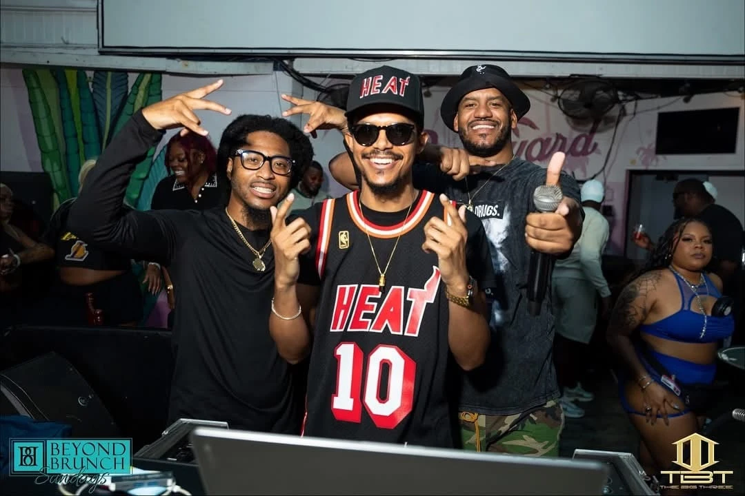 DJ BRE in a Miami Heat jersey with performers at a live event